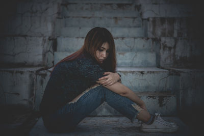 Full length of young woman sitting against wall