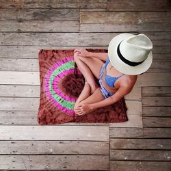 High angle view of woman sitting on exercise mat at wooden floor