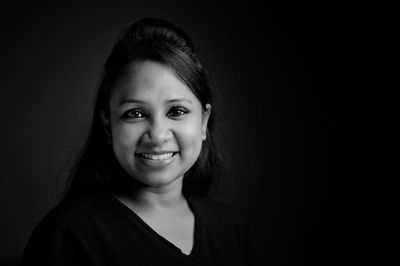 Portrait of smiling woman against black background