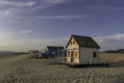 Beach hut by sea against sky