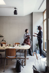 Full length of female colleagues eating lunch at perfume workshop