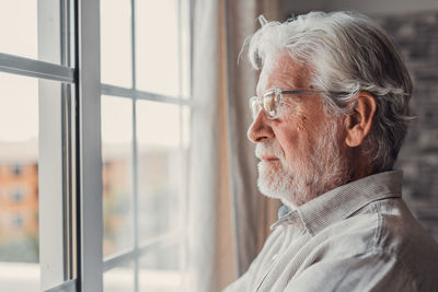 Thoughtful young man looking through window