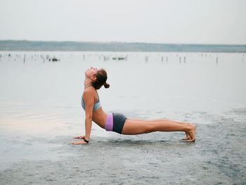 Full length of young woman on beach against sky