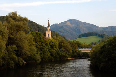 Scenic view of building by trees and mountains against sky