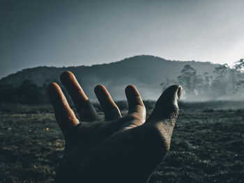 Hand of man gesturing against mountain