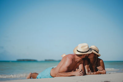 Man wearing hat on beach against clear sky