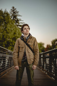 Portrait of young man standing against railing