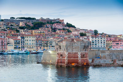 Buildings by sea against sky in town