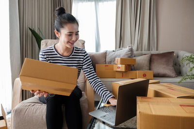 Young woman reading book while sitting on sofa at home