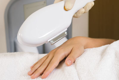 Cropped hands of woman doing laser treatment