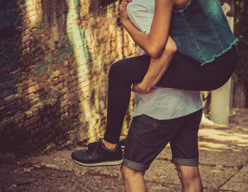 Midsection of boyfriend piggybacking girlfriend outdoors