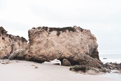 Rock formations on beach against clear sky