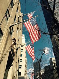Low angle view of flags and buildings against sky