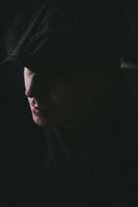 Close-up of young man wearing flat cap in darkroom