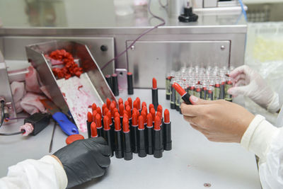 Cropped hands of people making lipstick in factory