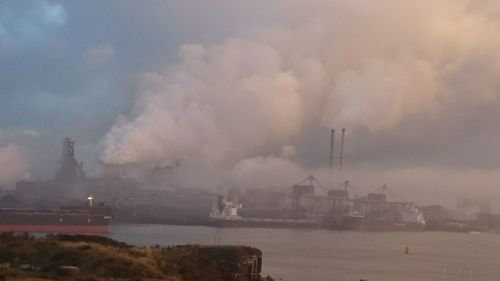 Smoke emitting from factory against sky