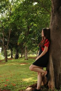 Side view of young woman standing on tree