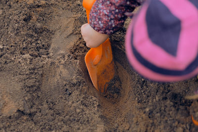 Girl playing with shovel on sand 