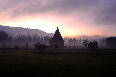 View of temple building on land against sky during sunset