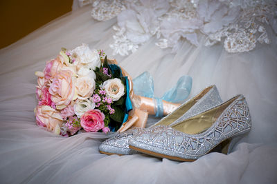 Close-up high angle view of bouquet and shoes on wedding dress