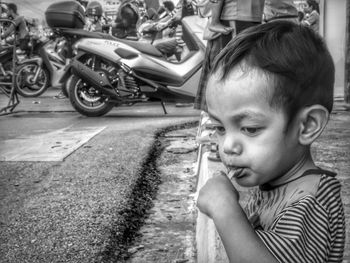 Cute boy eating lollipop while looking down on street