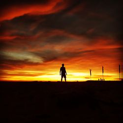 Silhouette man standing against orange sky