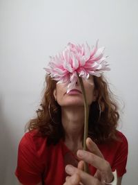 Close-up of woman holding pink flower against white background