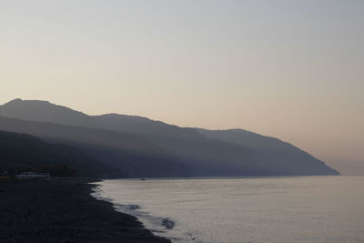 Scenic view of sea and mountains against clear sky