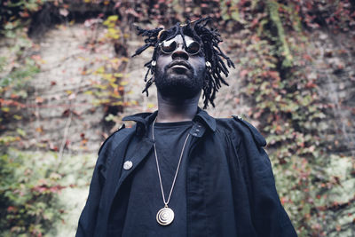 Portrait of man standing against plants in forest