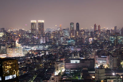 Illuminated buildings in city against sky at night