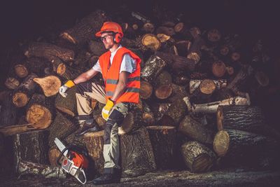 Portrait of man sitting on log at night