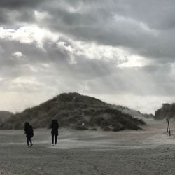 Rear view of men walking on landscape against sky