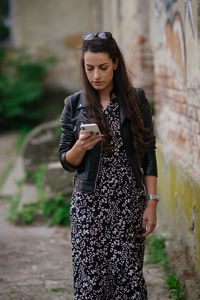 Beautiful woman in dress and leather jacket surfing on her phone