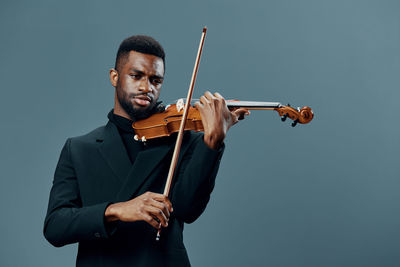 Young man playing violin against white background