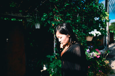 Side view of young woman looking at plants