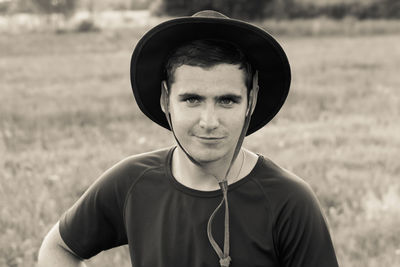 Closeup portrait of millennial man with cowboy hat, standing on nature background, outdoors.