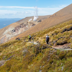 Rear view of people walking on land against sky