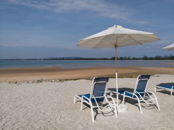 Chairs on beach by sea against sky