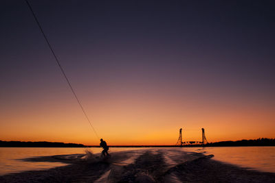 Silhouette man wakesurfing during sunset