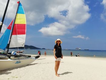 Portrait of woman standing at beach against sky