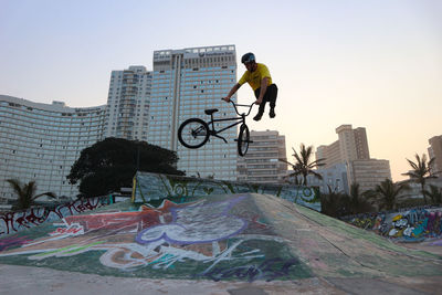 Full length of man skateboarding on building against clear sky