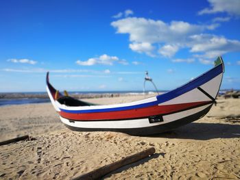 Boat moored on beach against sky