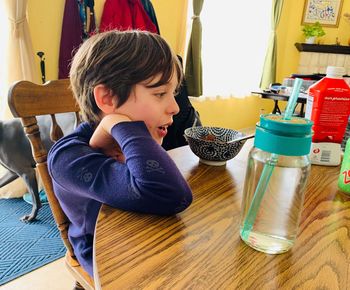 Rear view of boy looking down while sitting on table