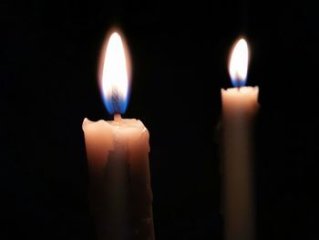 Close-up of illuminated candles against black background