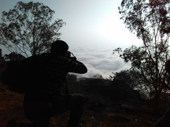 Silhouette man standing by trees against sky