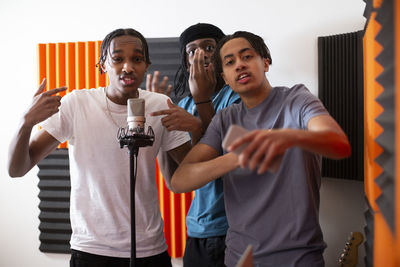 Portrait of teenage rappers gesturing while recording song in studio