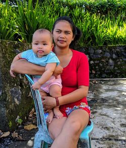 Portrait of mother and daughter sitting outdoors