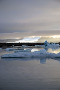 Scenic view of glacial lake with lotteria iceberg against sky