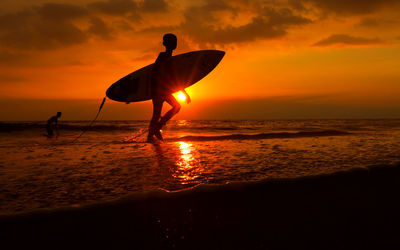 Silhouette of people on beach at sunset