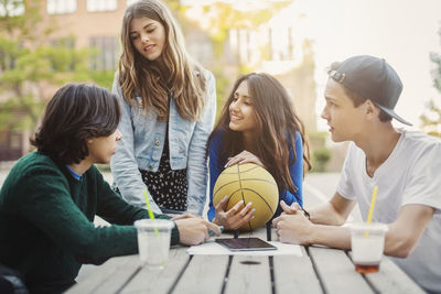 Happy teenagers discussing at table outdoors